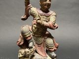 statue of a man sitting on a rock holding a sword