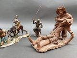 three figurines of people riding horses and a man on a sled