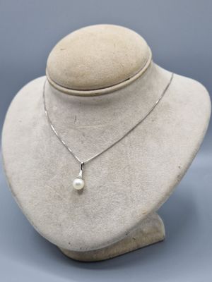 un gros plan d'un collier porté par un mannequin, orné d'une perle blanche