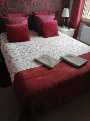 un lit orné d'oreillers et de couvertures rouges dans une chambre à coucher