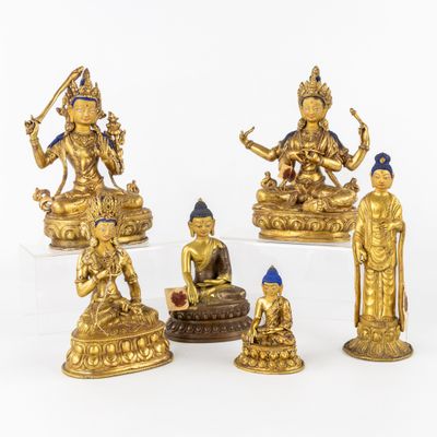 cinq figurines en or représentant des bouddhas assis sur une table