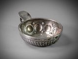 an old silver bowl with a spoon in it on a table