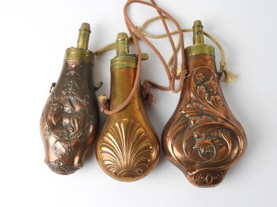 three antique brass bottle ornaments on a white surface