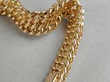 gold chain bracelet with a bell charm on a white surface