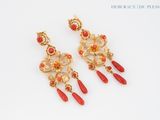 pair of red and gold earrings on a white surface