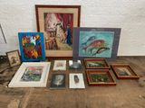 un ensemble d'œuvres d'art, encadrées et non encadrées, posées sur une table