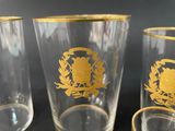 three glasses with gold designs on them sitting on a black surface