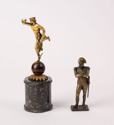 statue of a man standing on a pedestal next to a statue of a man on a ball