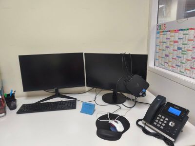 a desk with two monitors, a keyboard, a phone, and a telephone