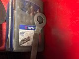 a close up of a wrench and a tool on a red surface