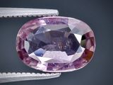 un gros plan d'un saphir rose tenu par une paire de pinces