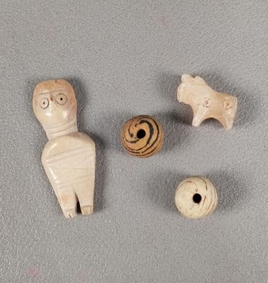 trois figurines en bois représentant des personnages et une balle posées sur une surface grise