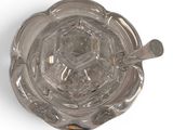 a glass ashtray on a white surface with a spoon in it