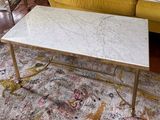 une table basse avec un plateau en marbre posée sur un tapis dans un salon