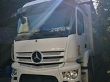 un camion blanc garé devant des arbres