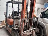 un chariot élévateur garé dans un garage à côté d'une camionnette blanche