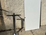 a white board leaning against a wall next to a metal pole