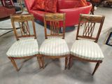three chairs with upholstered seats in a room with a red couch