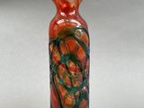 a red and green vase sitting on a white surface