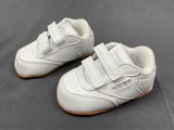 baby boy ' s white leather shoes with velcro straps on a grey background