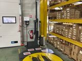 un chariot élévateur dans un entrepôt où se trouvent des cartons au sol