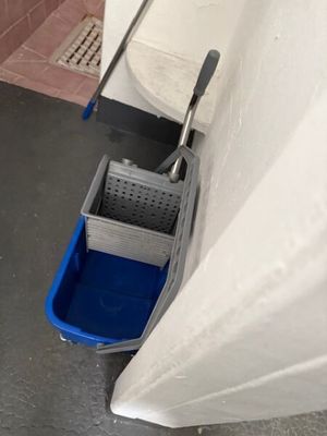 une serpillière et un seau dans un coin de la salle de bains