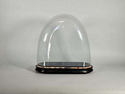 un dôme en verre reposant sur un socle en bois, sur fond blanc
