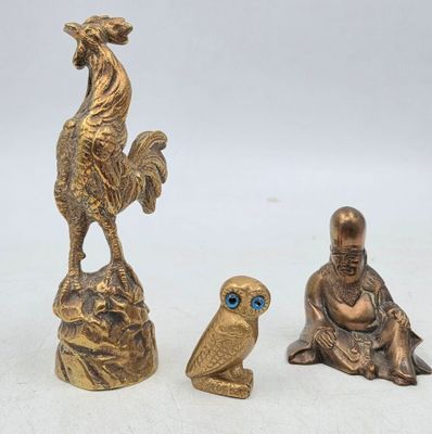 trois figurines en bronze représentant des oiseaux et un homme assis sur un rocher