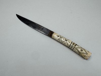 a close up of a knife on a table with a white background