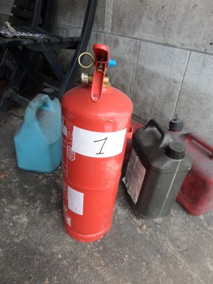 un extincteur rouge posé à côté de deux bidons bleus et d'un bidon rouge