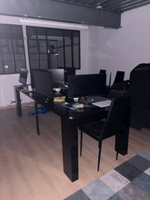 un bureau noir sur lequel se trouve un ordinateur, dans une pièce