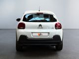 the rear end of a small white car parked in a room