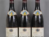 Trois bouteilles de vin sont alignées sur une table en verre
