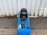 a blue air compressor sitting on the ground next to a white wall