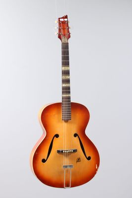 an image of a guitar hanging from a string on a wall