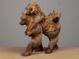 une sculpture en bois représentant un ours portant un ourson