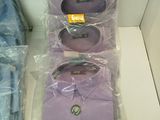 four shirts in plastic bags sitting on a shelf