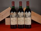 three bottles of red wine sitting on a table next to a wooden box