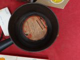 une poêle posée sur une table rouge, à côté d'un livre