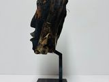 a close up of a sculpture of a head on a wooden stand