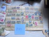 une pile de vieux timbres posée sur une table, à côté d'une pancarte bleue
