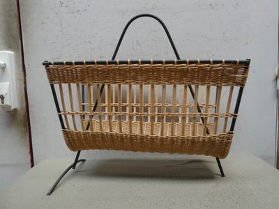 un panier en osier posé sur un support, muni d'une poignée noire