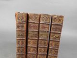 four old books are stacked on top of each other on a table