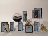 Des flacons de parfum sont disposés sur une table, à côté d'un vase en verre