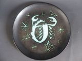 une assiette noire ornée d'un motif vert et blanc