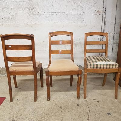 Trois chaises en bois sont alignées contre un mur de briques blanches