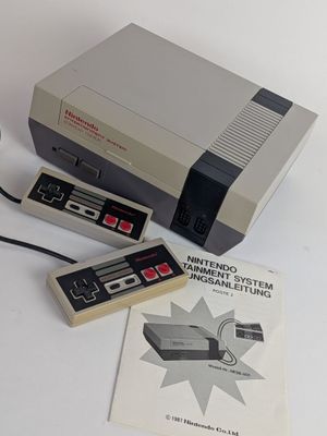 an old nintendo game system sitting on a table next to a book