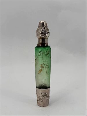 a green glass bottle with a silver lid on a white surface