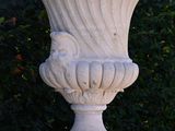a white vase sitting on top of a stone pedestal