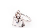 un gros plan d'une bague en argent sur laquelle est représenté un sac à main